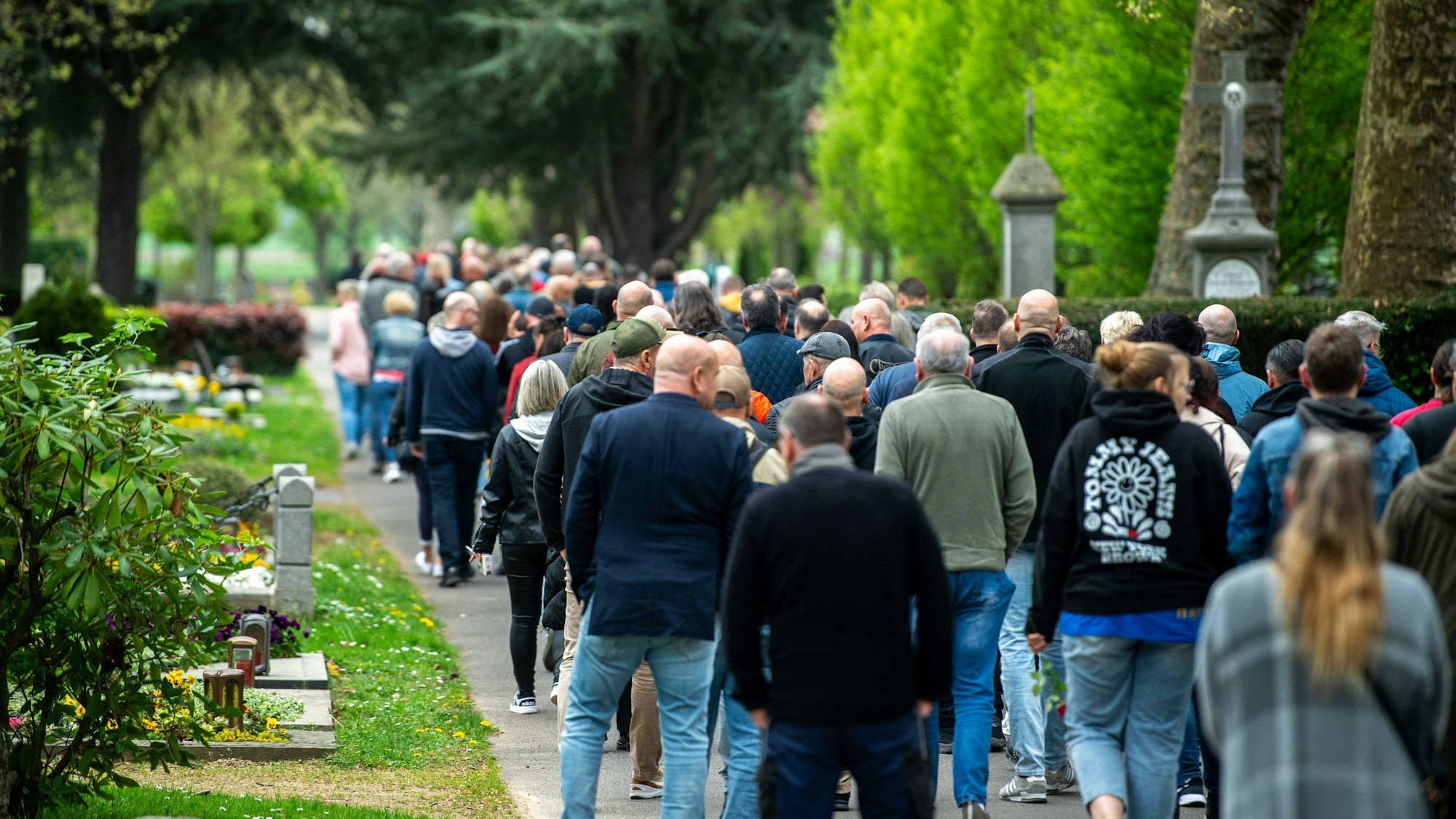 Trauergäste laufen über den Friedhof.