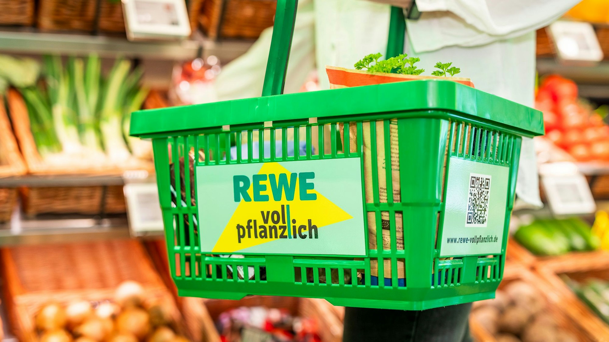 Zu sehen ist ein grüner Einkaufskorb in einem Supermarkt.