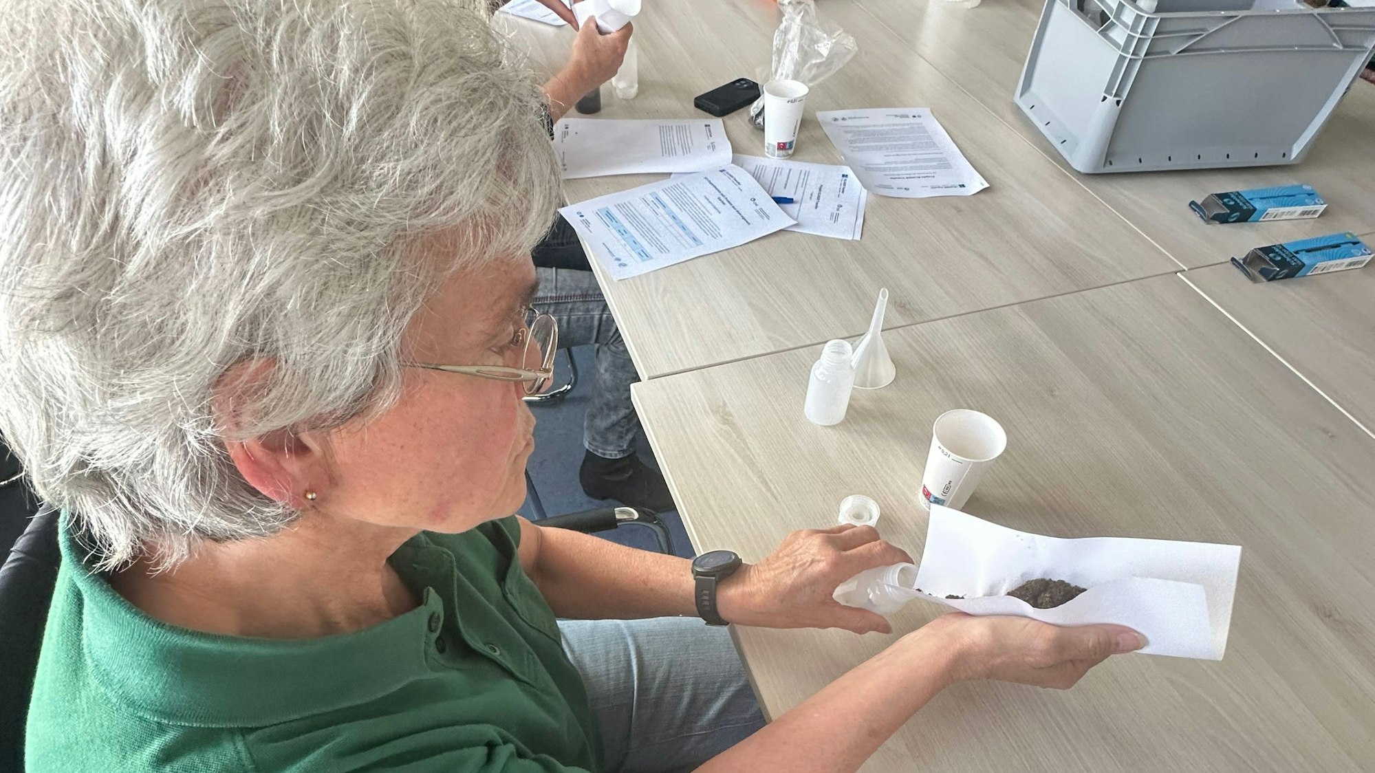 Brigitte Klöckner aus Hangelar füllt ihre mitgebrachte Erde in eine Analyseflasche.