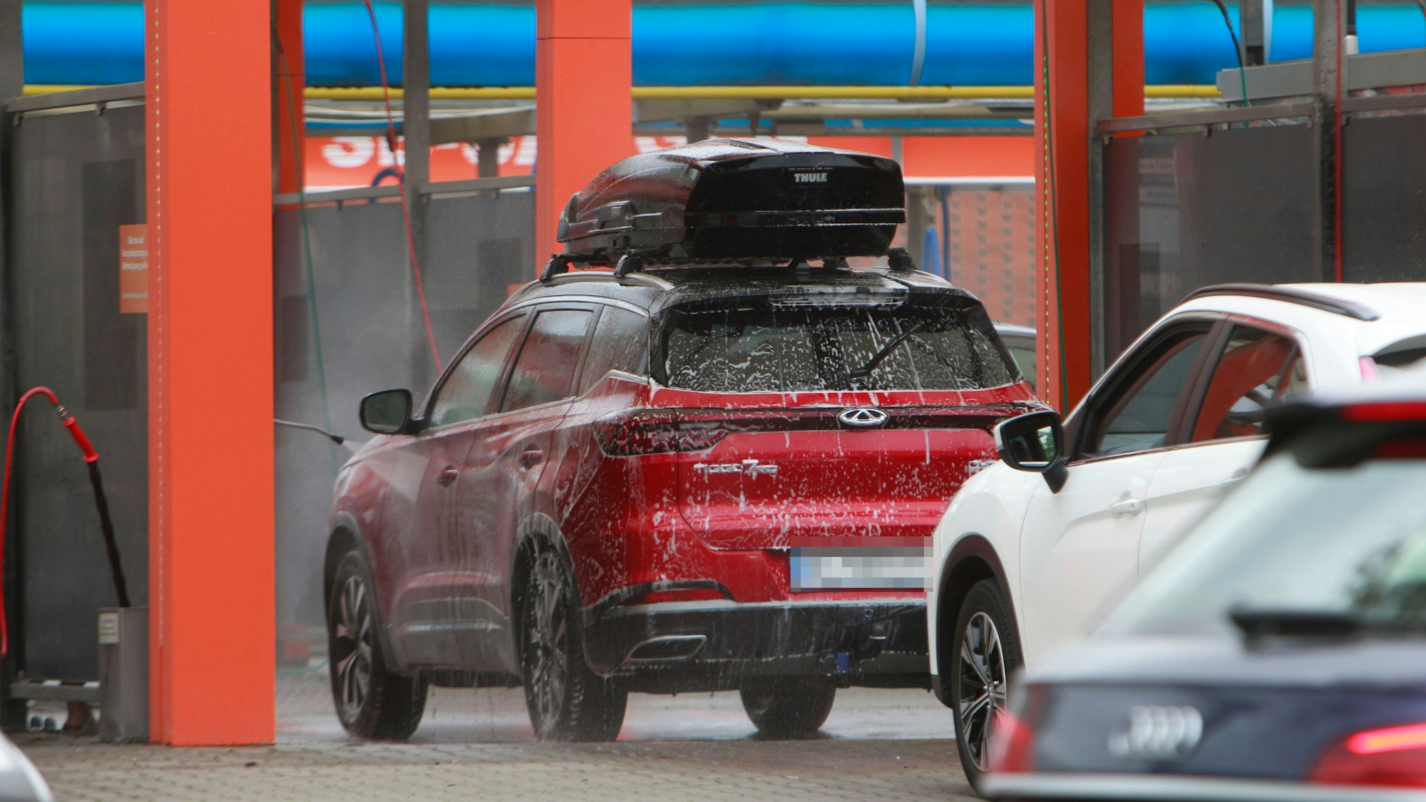 Ein rotes Auto steht in der Autowaschanlage.