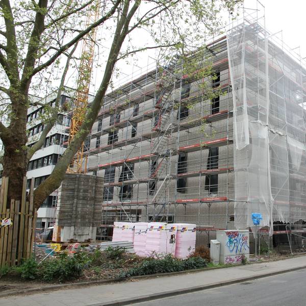 Die Baustelle für ein großes, eingerüstetes Haus mit verhängter Fassade
