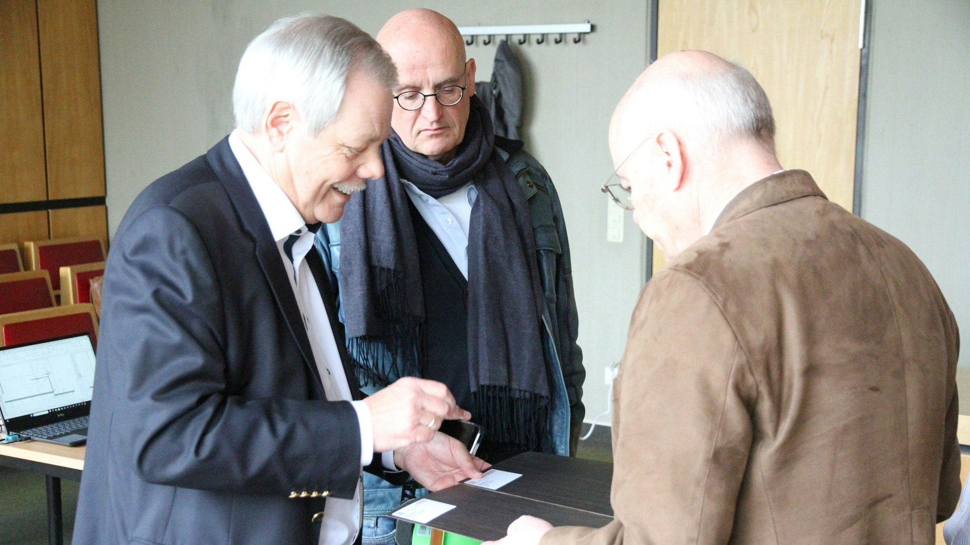 Drei Männer schauen sich Holzmuster für Möbel an