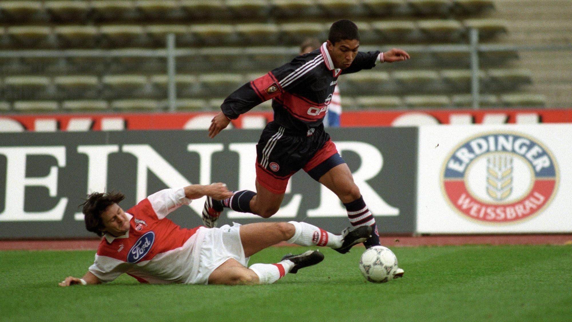 Ein Fußballspieler grätscht seinem Gegenspieler den Ball weg.