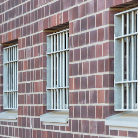 Die Fenster einer Justizvollzugsanstalt sind vergittert.