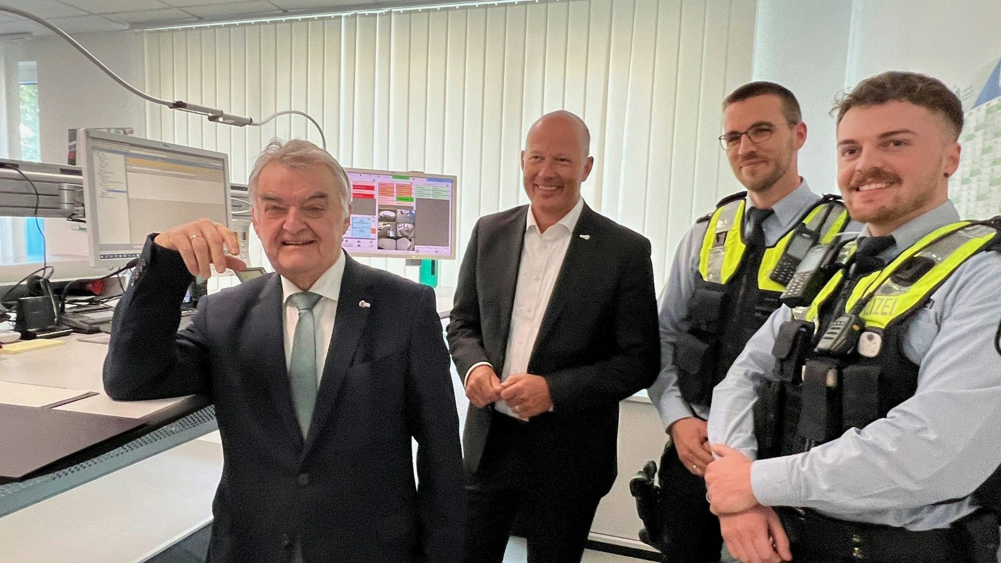 Das Bild zeigt NRW-Innenminister Herbert Reul und Landrat Frank Rock sowie zwei Polizeibeamte in der neuen Wache in Lechenich.