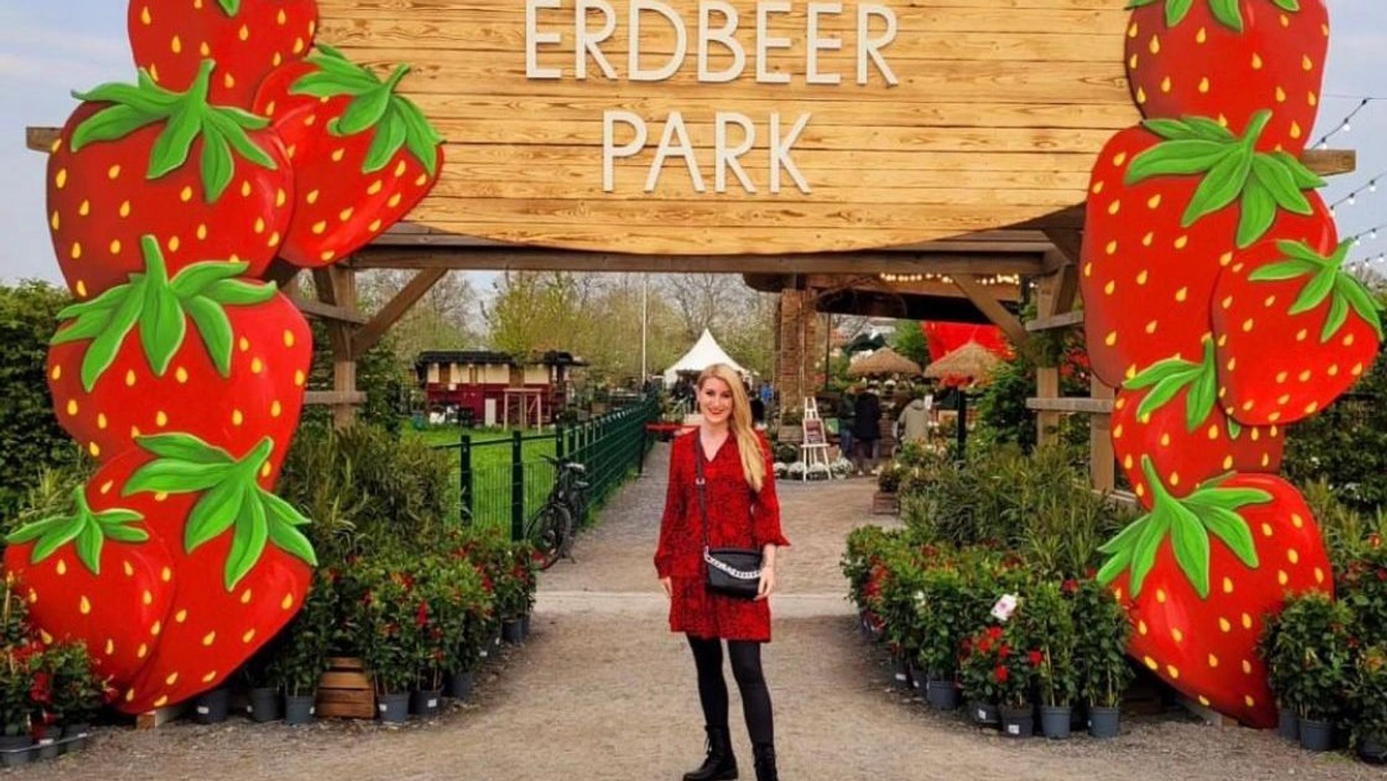 Auf dem Foto ist eine Besucherin vor einem Bogen aus überdimensionalen Erdbeeren zu sehen.