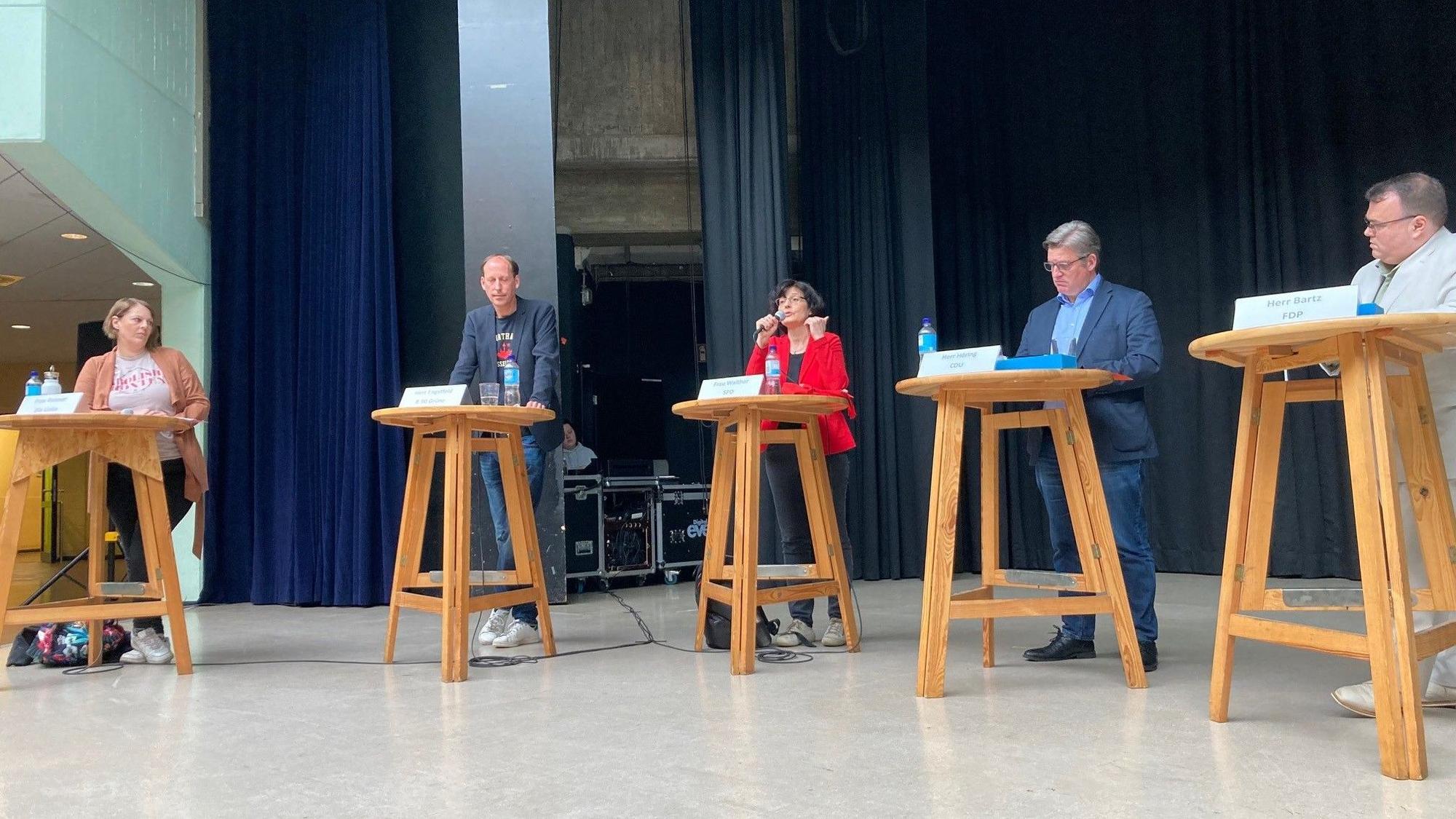 Die fünf Kandidaten stehen an einzelnen Stehtischen.