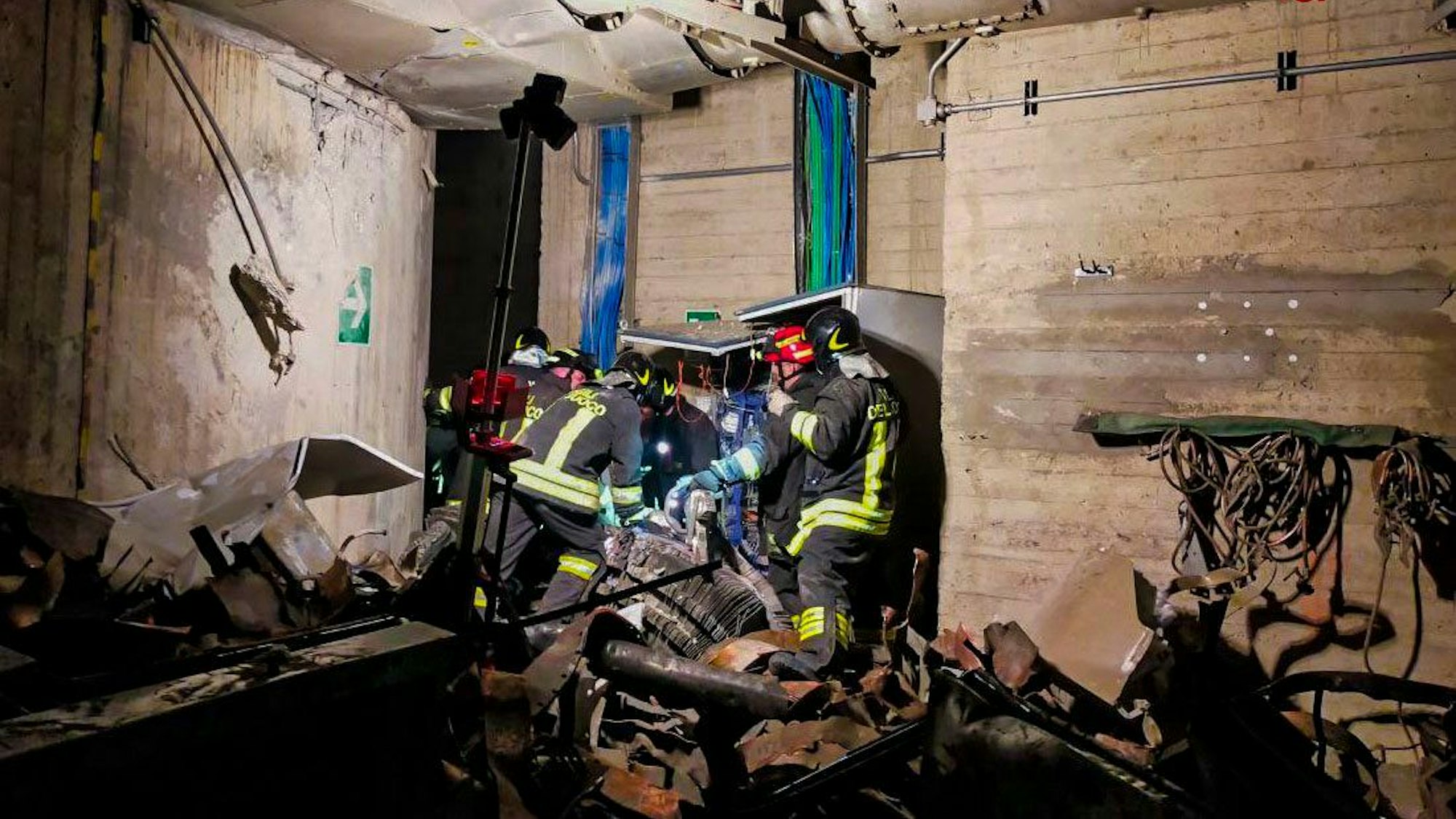Feuerwehrleute werden in einem Raum, in dem Trümmerschutt liegt, angeleuchtet.