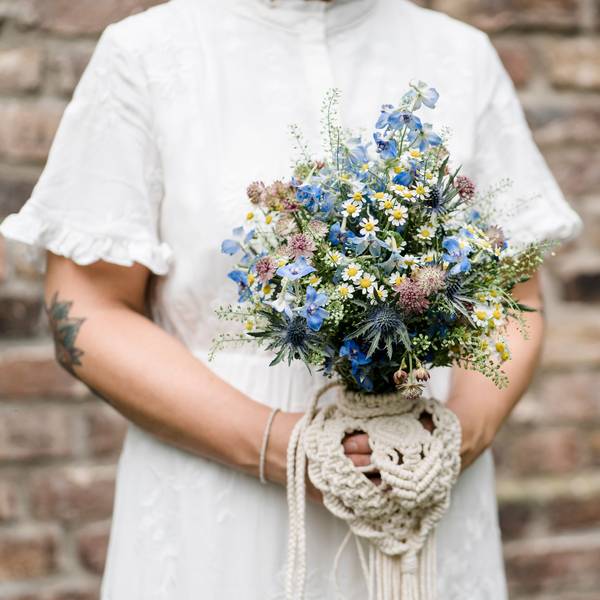 Eine Braut trägt ein Secondhand-Hochzeitskleid, der Brautstrauß besteht aus regionalen Wiesenblumen.