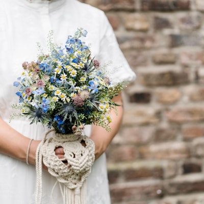 Eine Braut trägt ein Secondhand-Hochzeitskleid, der Brautstrauß besteht aus regionalen Wiesenblumen.
