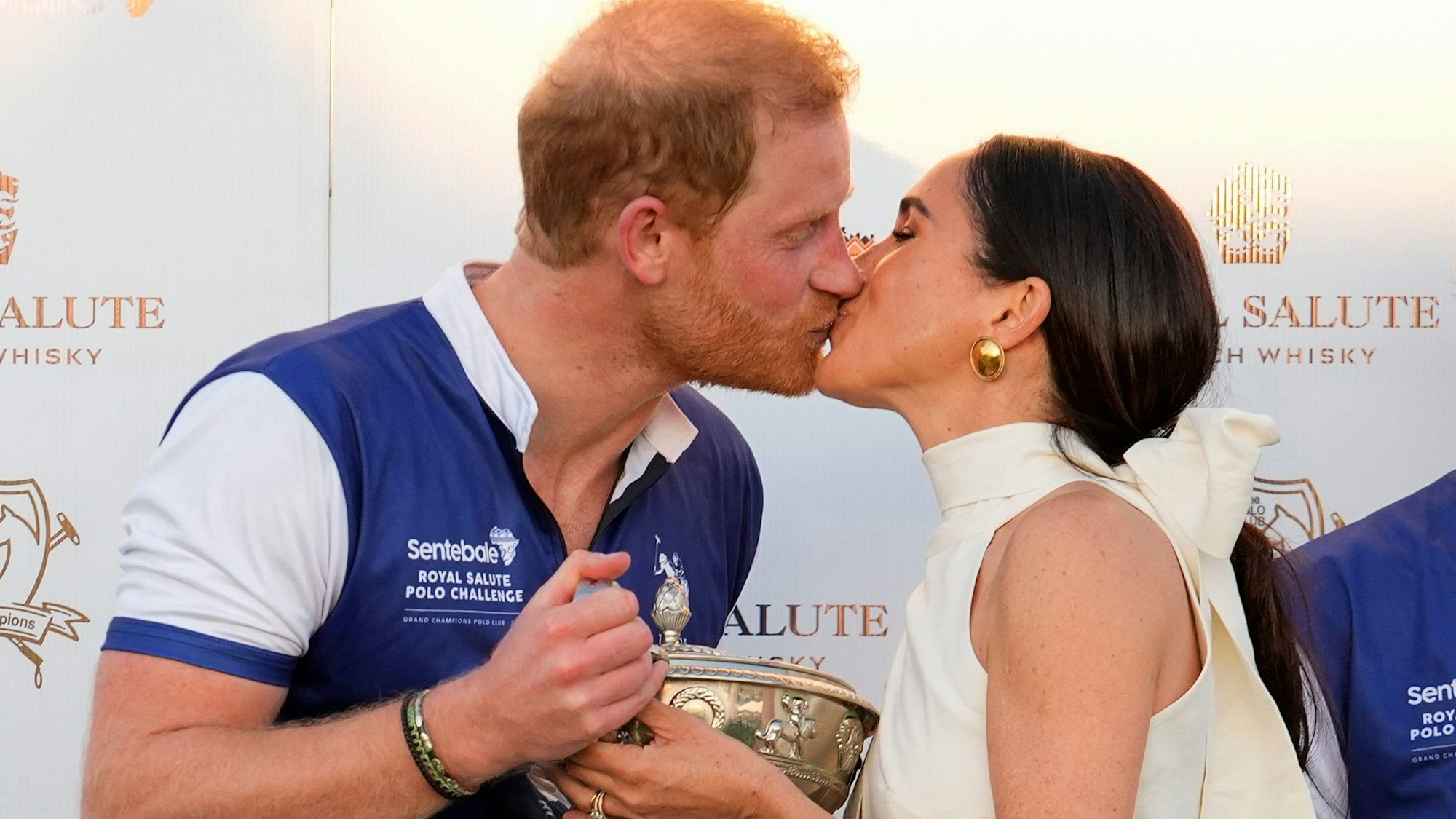 Der britische Prinz Harry (l), und seine Frau Meghan küssen sich, während sie seinem Polo-Team die Trophäe für den Sieg bei der Royal Salute Polo Challenge to Benefit Sentebale überreicht.