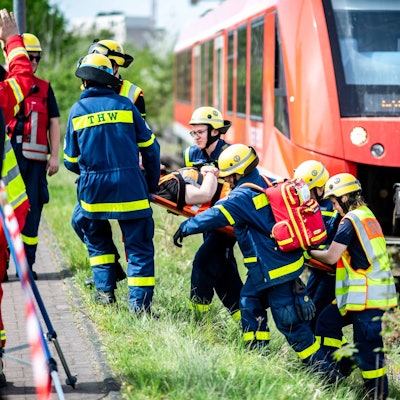 Das Bild zeigt einige Mitarbeiter des THW, die eine verletzte Person eine Böschung hinauf tragen.