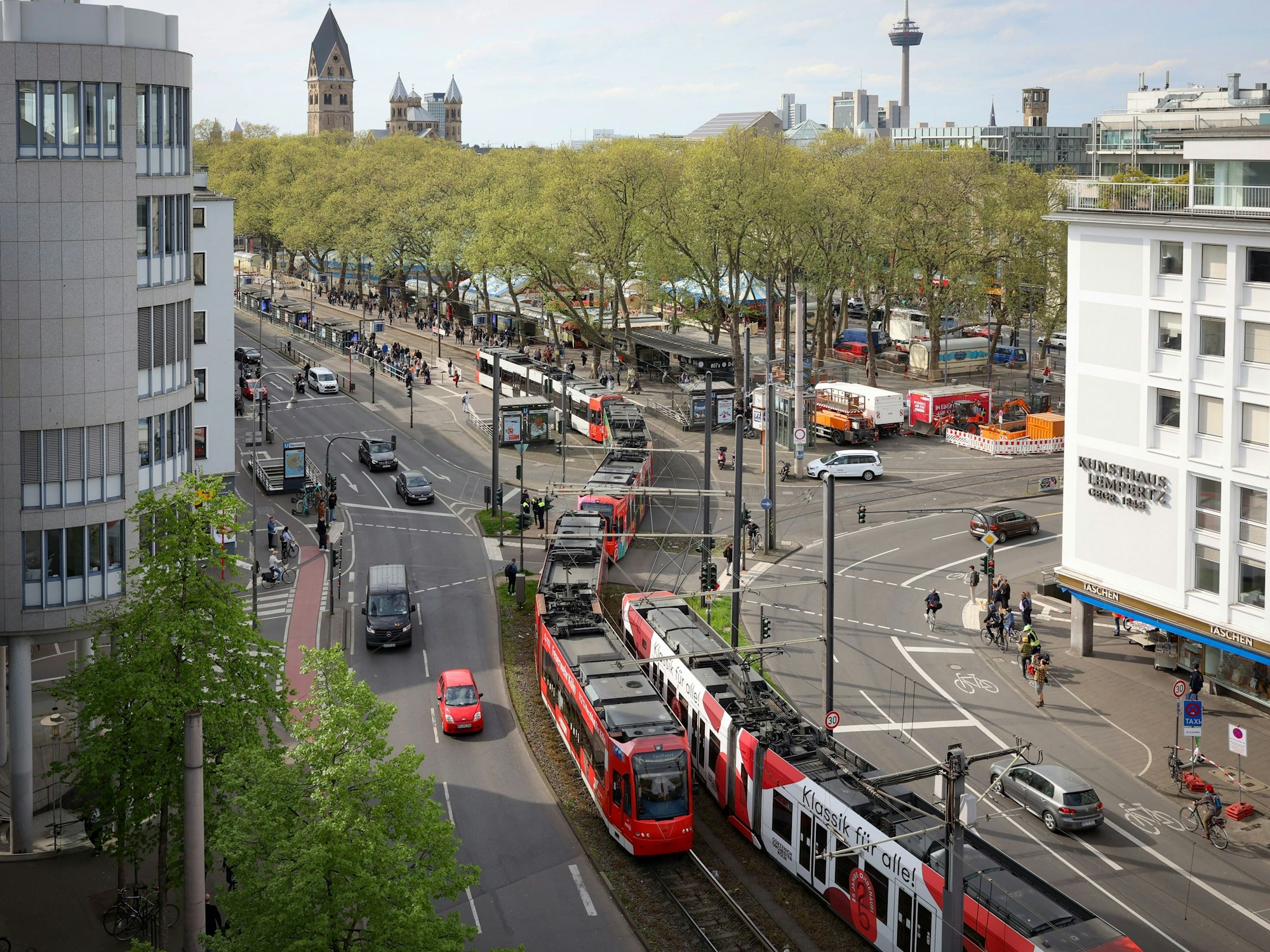 Eine Bahn der KVB, bestehend aus drei Waggons, schlängelt sich durch Straßen in der Innenstadt.