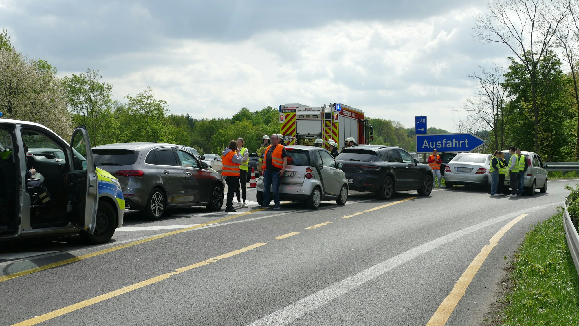 Mehrere Fahrzeuge stehen auf der Fahrspur der Ausfahrt, dazwischen Menschen mit Warnwesten.