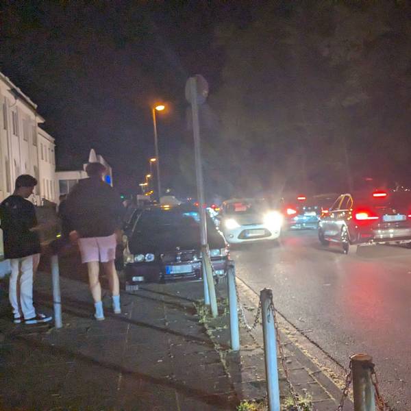 Autos fahren die Alfred-Schütte-Allee in der Nacht entlang.