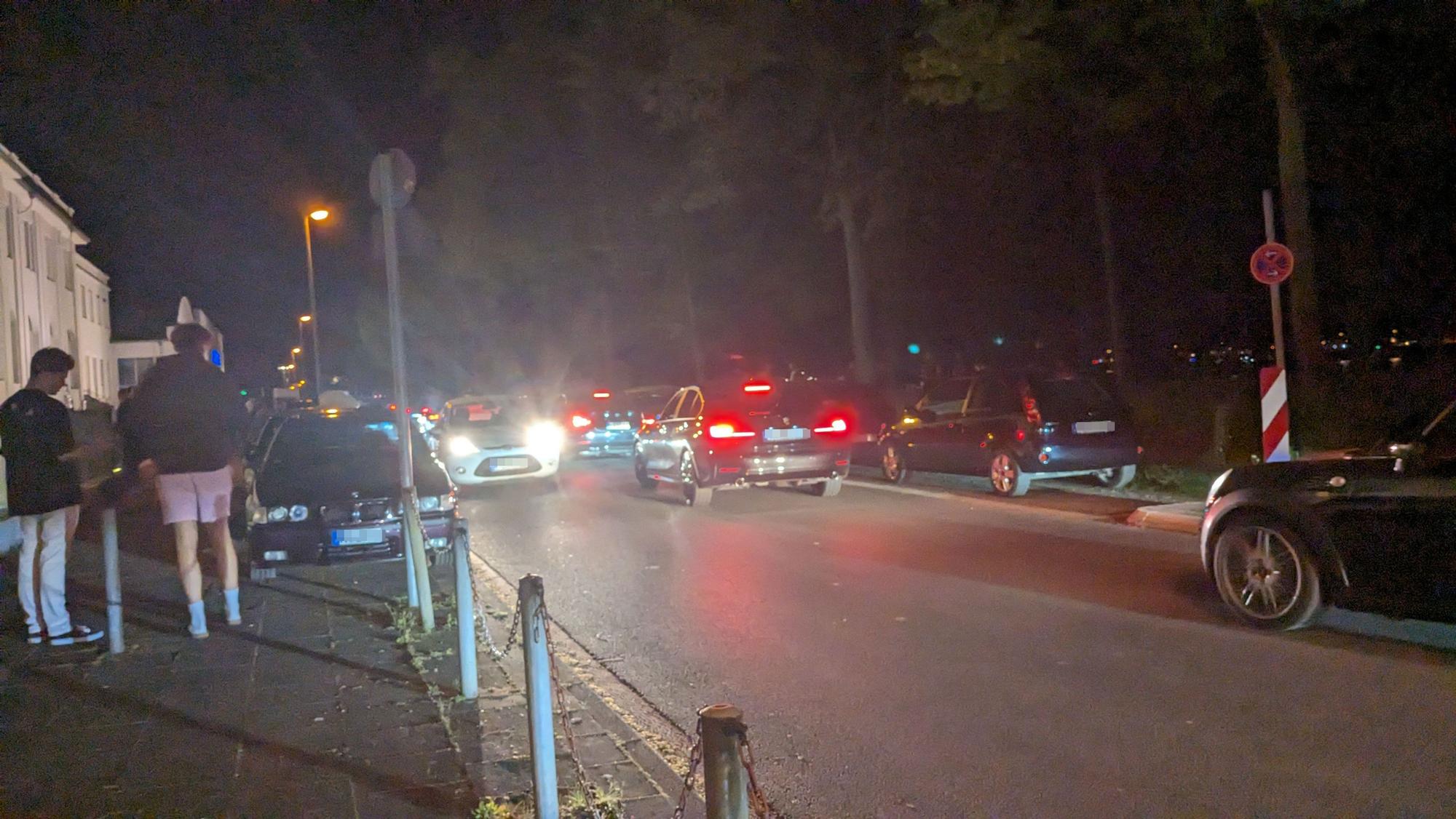 Autos fahren die Alfred-Schütte-Allee in der Nacht entlang.