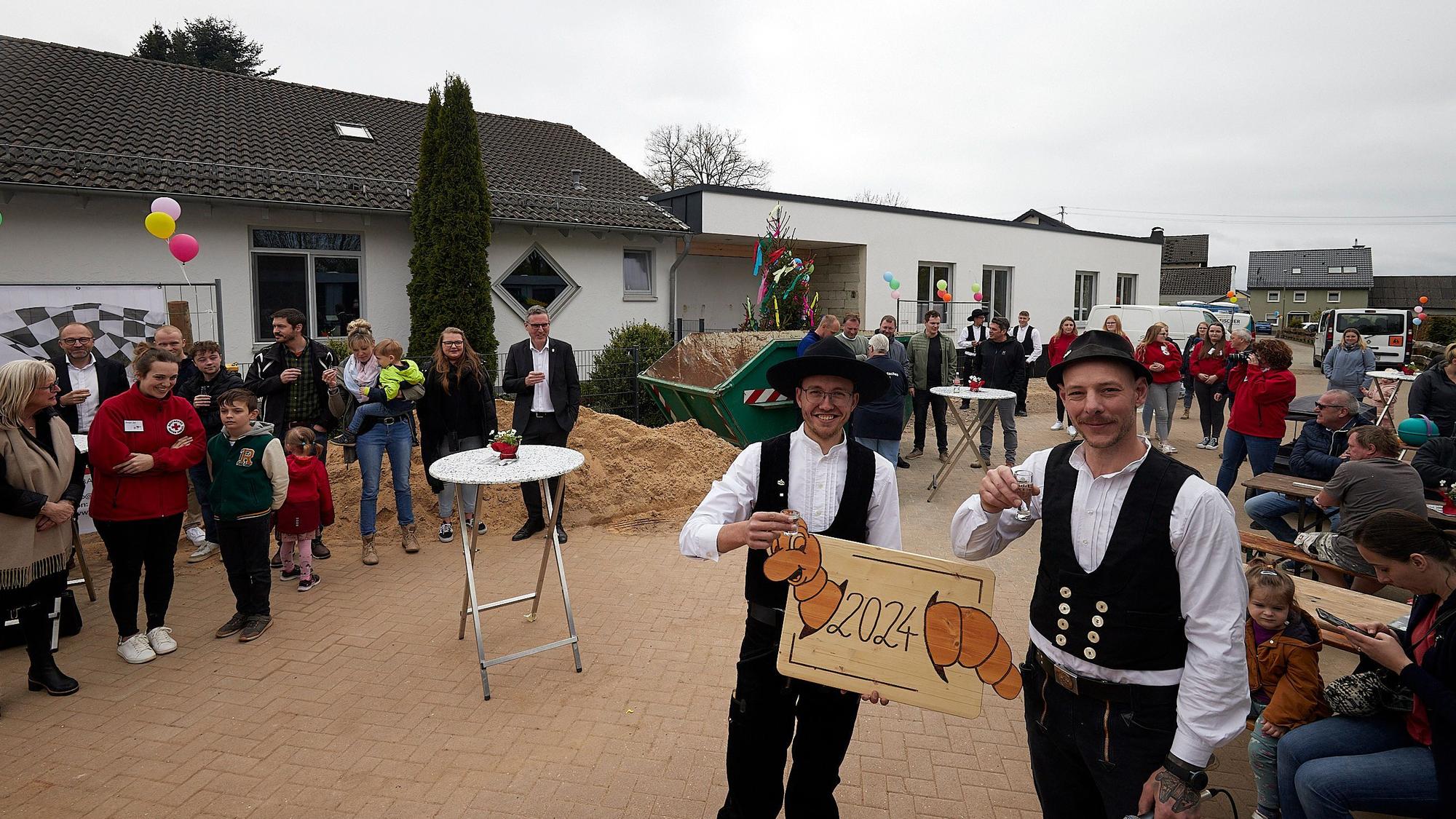 Tobias Kügler steht vorne rechts mit einem Glas in der Hand. Neben ihm steht ein Kollege von ihm, drumherum Zuschauer.