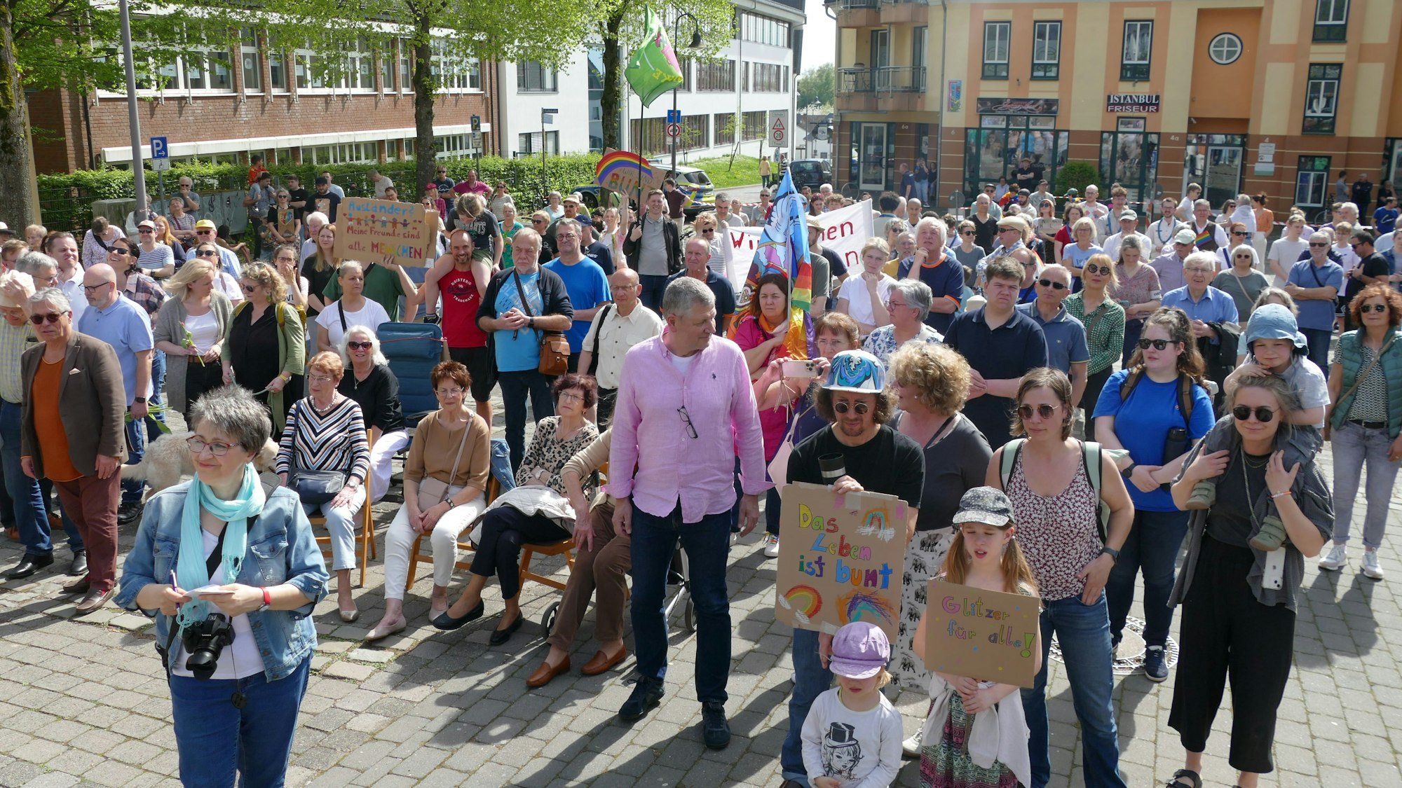 Menschen, zum Teil mit bunt beschriebenen Pappschildern, stehen auf dem Marktplatz in Neunkirchen-Seelscheid.