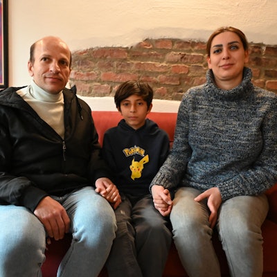 Das Bild zeigt die iranische Familie. Sie sitzen auf einem roten Sofa.