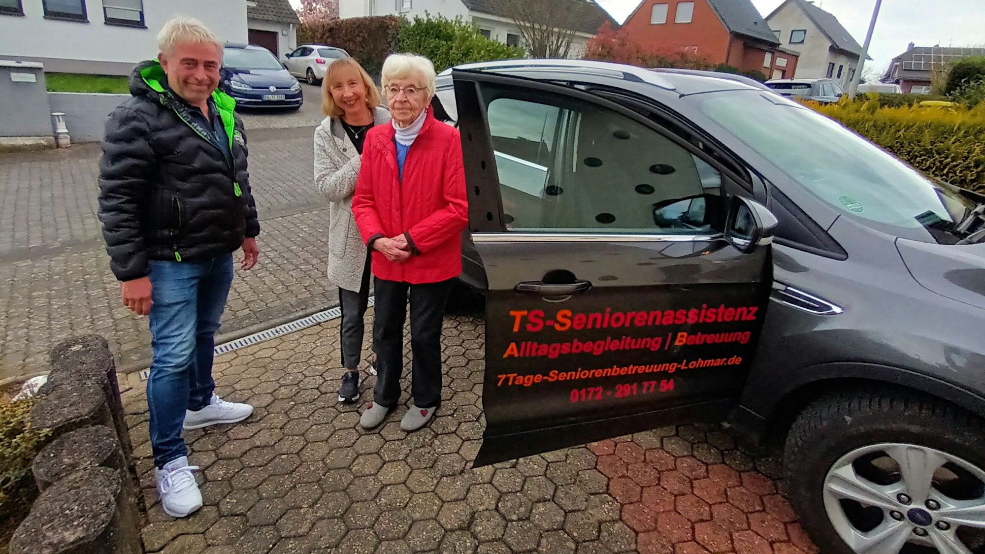 Ein Mann und zwei Frauen stehen an einem Auto