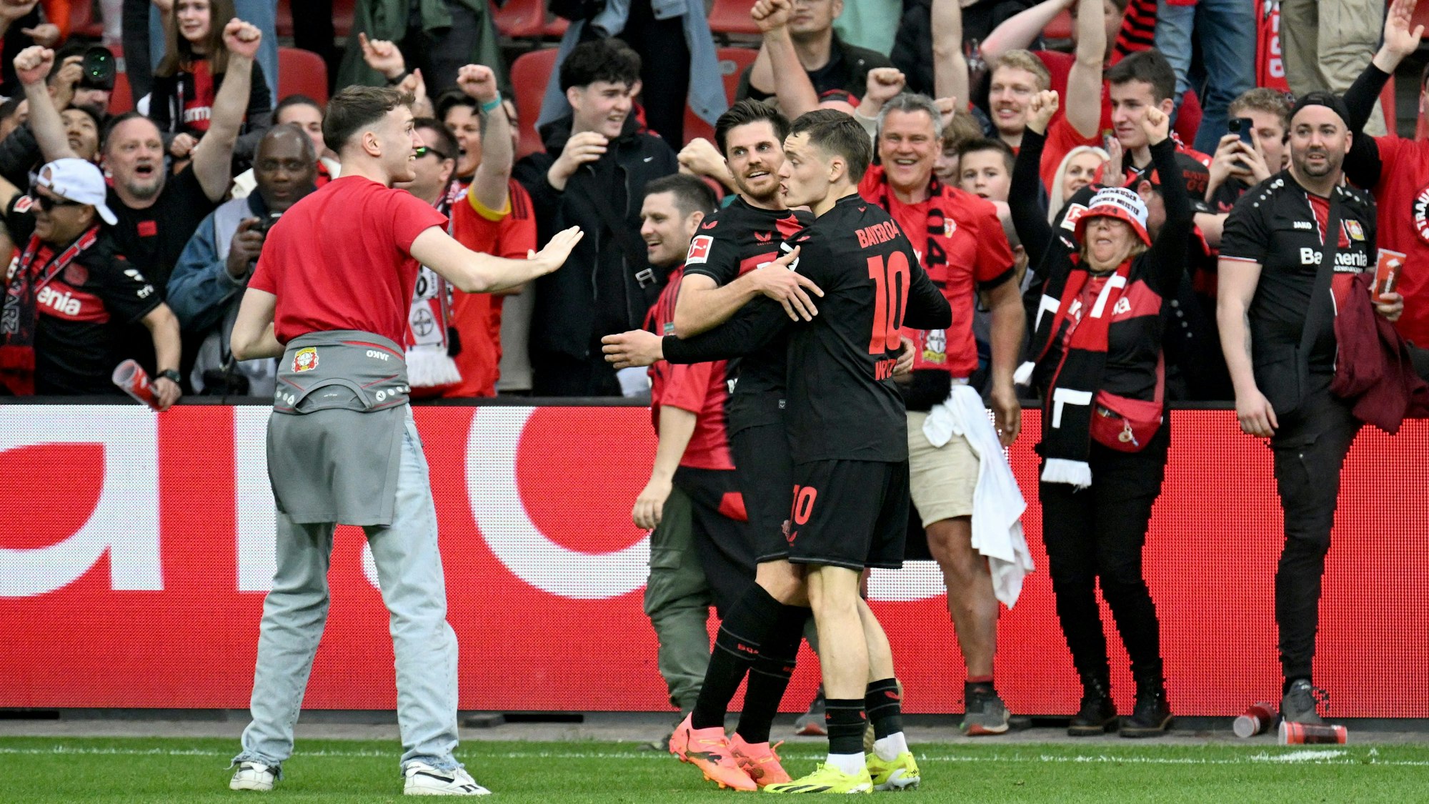 Leverkusen-Profi Florian Wirtz bittet nach seinem Tor einen Bayer-Fan, den Rasen zu verlassen.