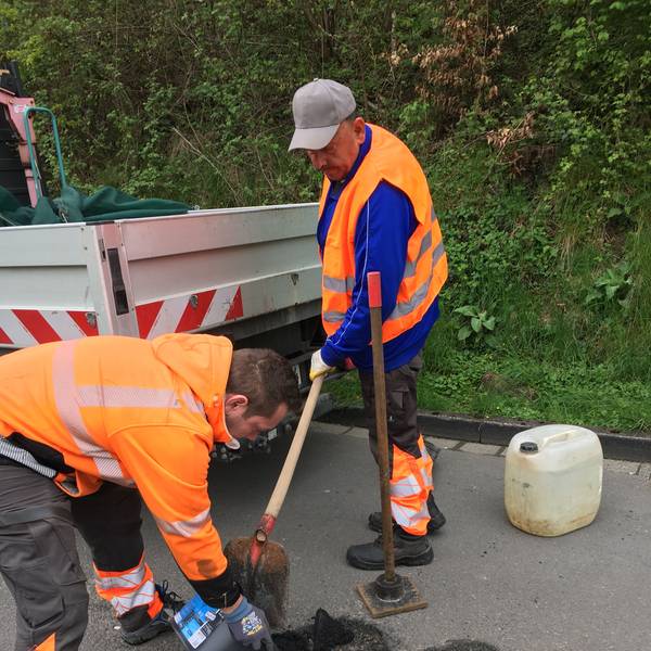 Ein Mitarbeiter des Gummersbacher Baubetriebshofs verfüllt im Stadtteil Berstig ein Schlagloch mit frischem Asphalt.
