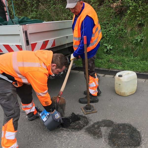 Ein Mitarbeiter des Gummersbacher Baubetriebshofs verfüllt im Stadtteil Berstig ein Schlagloch mit frischem Asphalt.