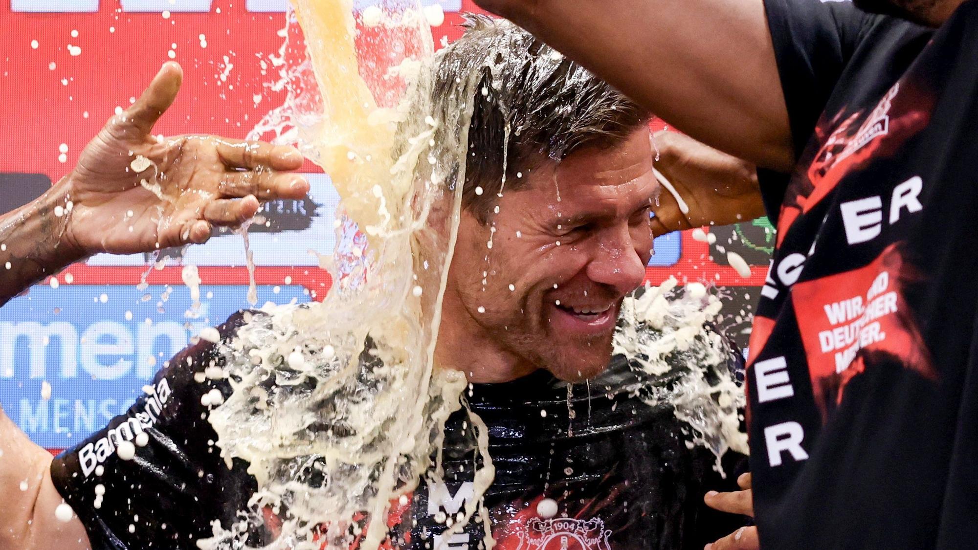 Leverkusens Trainer Xabi Alonso wird bei der Pressekonferenz nach dem Spiel von seinen Spielern mit Bier übergossen.