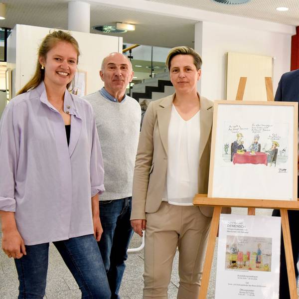 Zwei Männer und drei Frauen haben sich um eine Bild gruppiert.