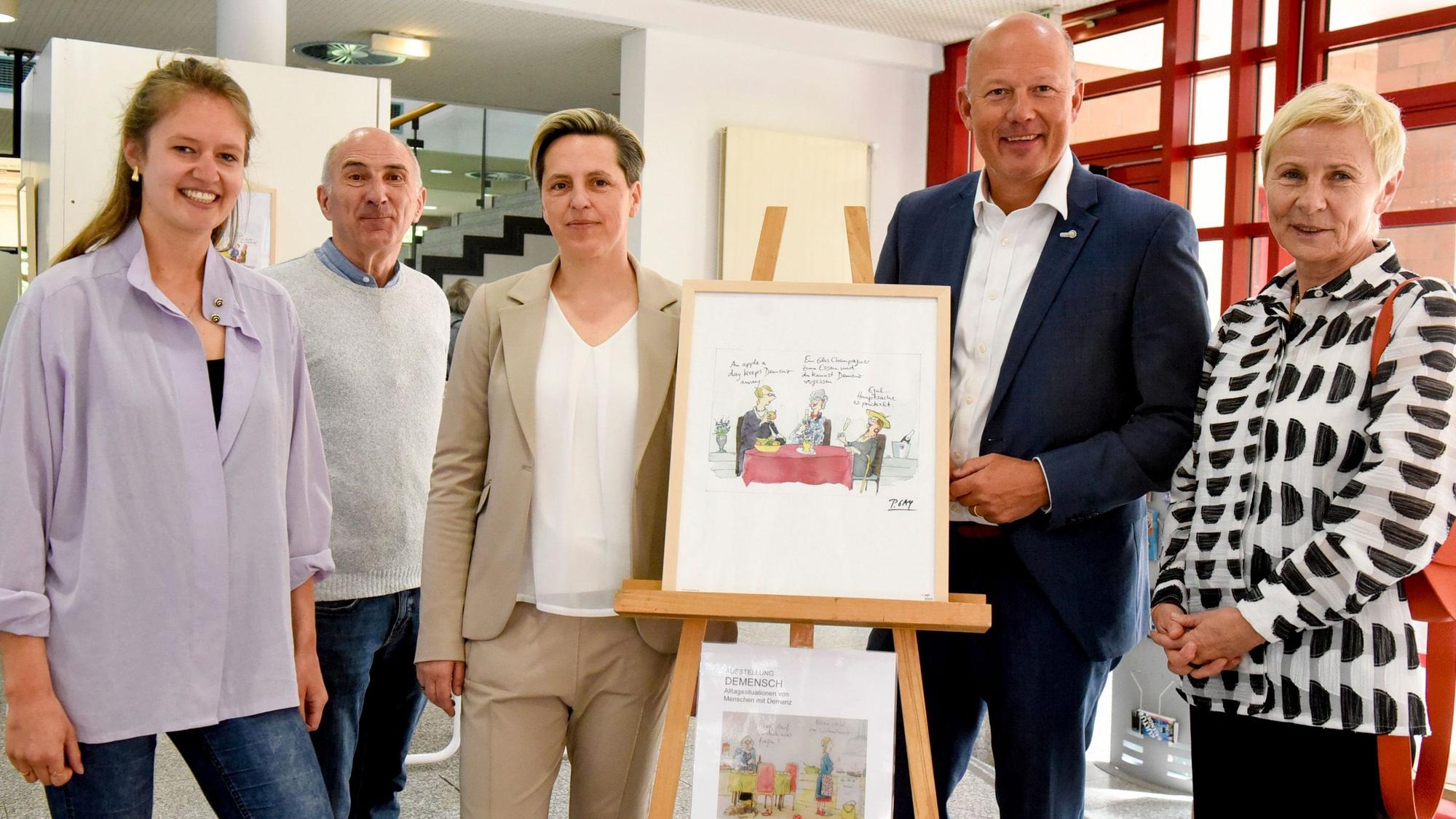 Zwei Männer und drei Frauen haben sich um eine Bild gruppiert.