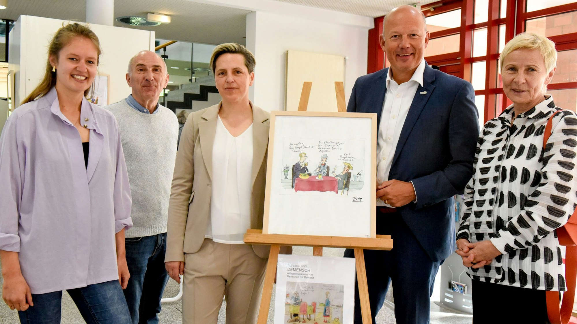 Zwei Männer und drei Frauen haben sich um eine Bild gruppiert.