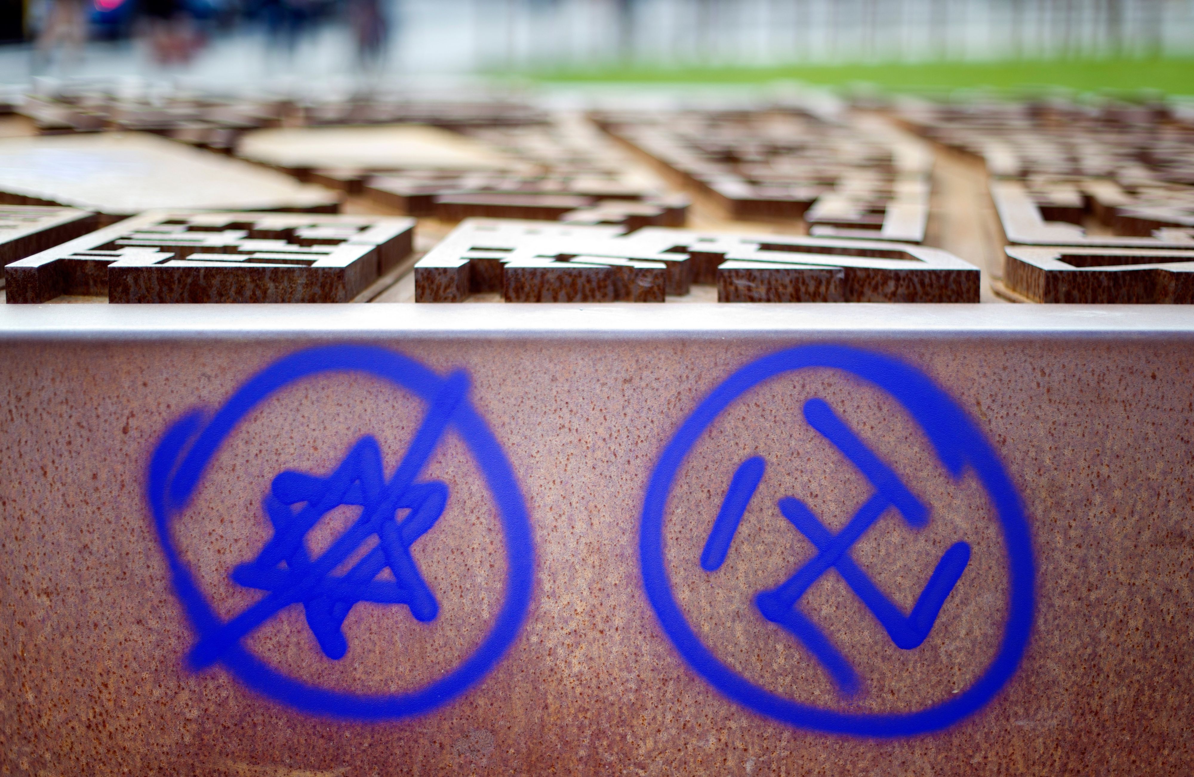 Ein Hakenkreuz und ein durchgestrichener Davidstern sind an einer Gedenkstätte zu sehen.