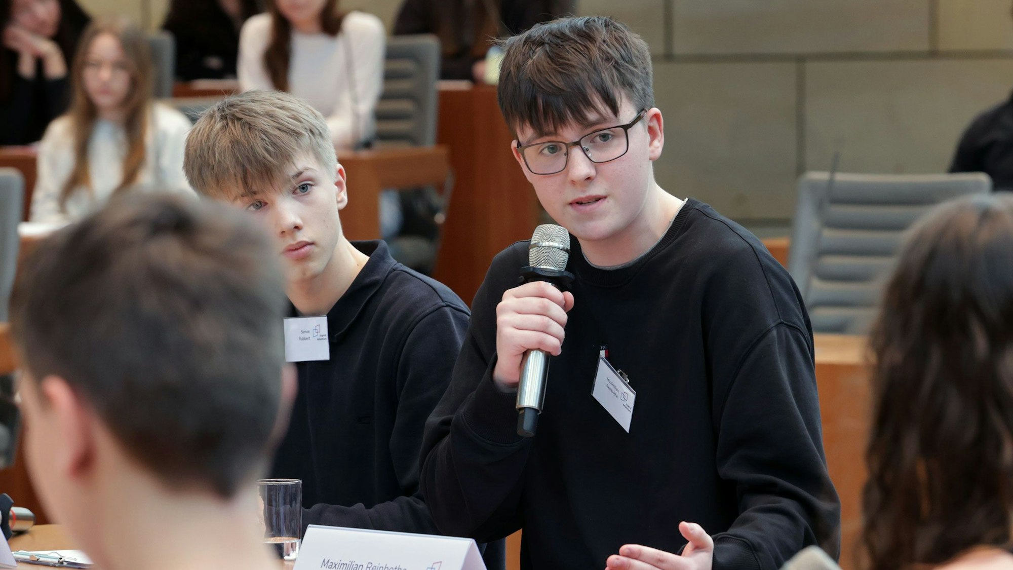 Max Reinbothe während der Debatte, er hält ein Mikrofon in der Hand.