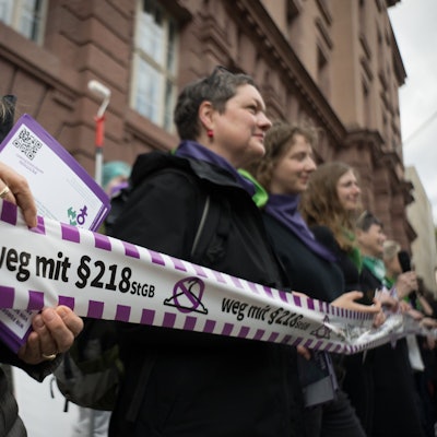 Aktivistinnen halten während eines Flashmobs des Bündnisses für sexuelle Selbstbestimmung unter dem Motto „Legal, einfach, fair - Für eine Neuregelung des Schwangerschaftsabbruchs in Deutschland!“ ein Band mit einem durchgestrichenen Kleiderbügel und dem Schriftzug „weg mit dem ß218 StGB“.