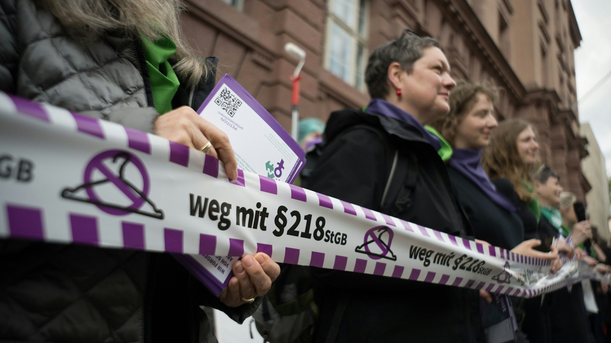 Aktivistinnen halten während eines Flashmobs des Bündnisses für sexuelle Selbstbestimmung unter dem Motto „Legal, einfach, fair - Für eine Neuregelung des Schwangerschaftsabbruchs in Deutschland!“ ein Band mit einem durchgestrichenen Kleiderbügel und dem Schriftzug „weg mit dem ß218 StGB“.