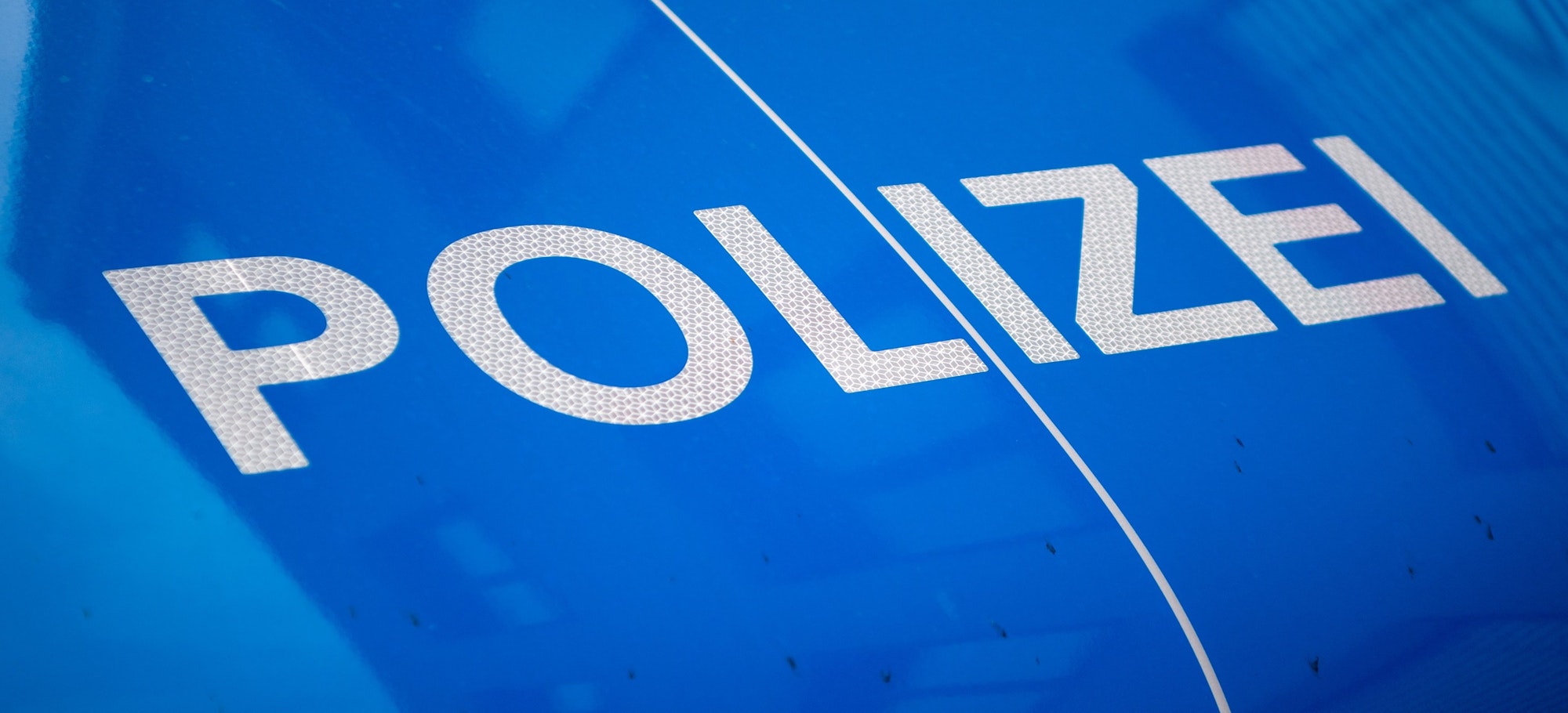 Das Bild zeigt die Aufschrift „Polizei“ auf einem Streifenwagen.