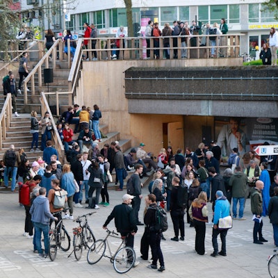 Zu sehen ist die Freitreppe am Ebertplatz in der Vorderansicht und eine große Menschenansammlung.