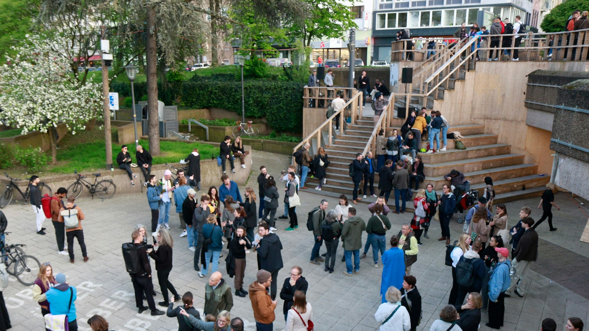 Zu sehen ist die Freitreppe auf dem Ebertplatz. Davor und darauf stehen Menschen.