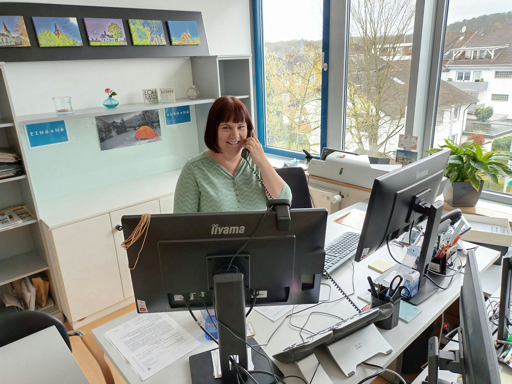 Eine Frau sitzt an einem Schreibtisch und telefoniert