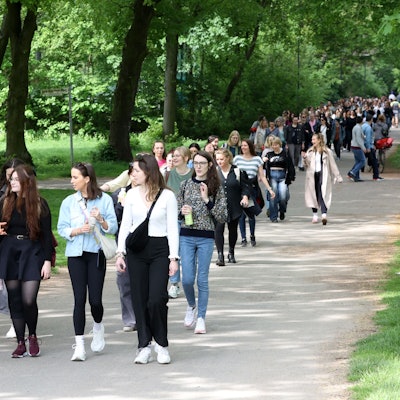 Frauen spazieren in einer großen Gruppe durch einen Park und unterhalten sich.