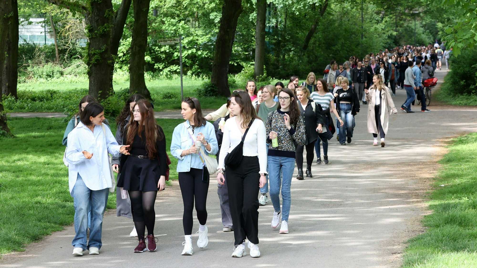 Frauen spazieren in einer großen Gruppe durch einen Park und unterhalten sich.
