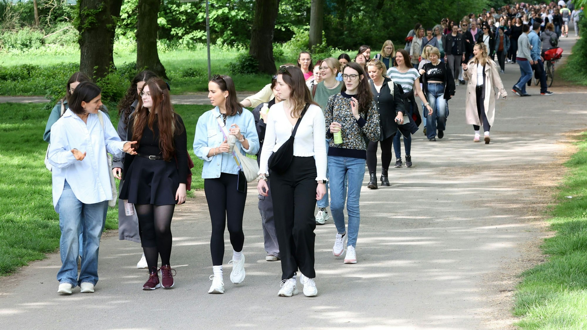 Zu sehen ist eine Gruppe von Frauen, die durch einen Park spaziert.