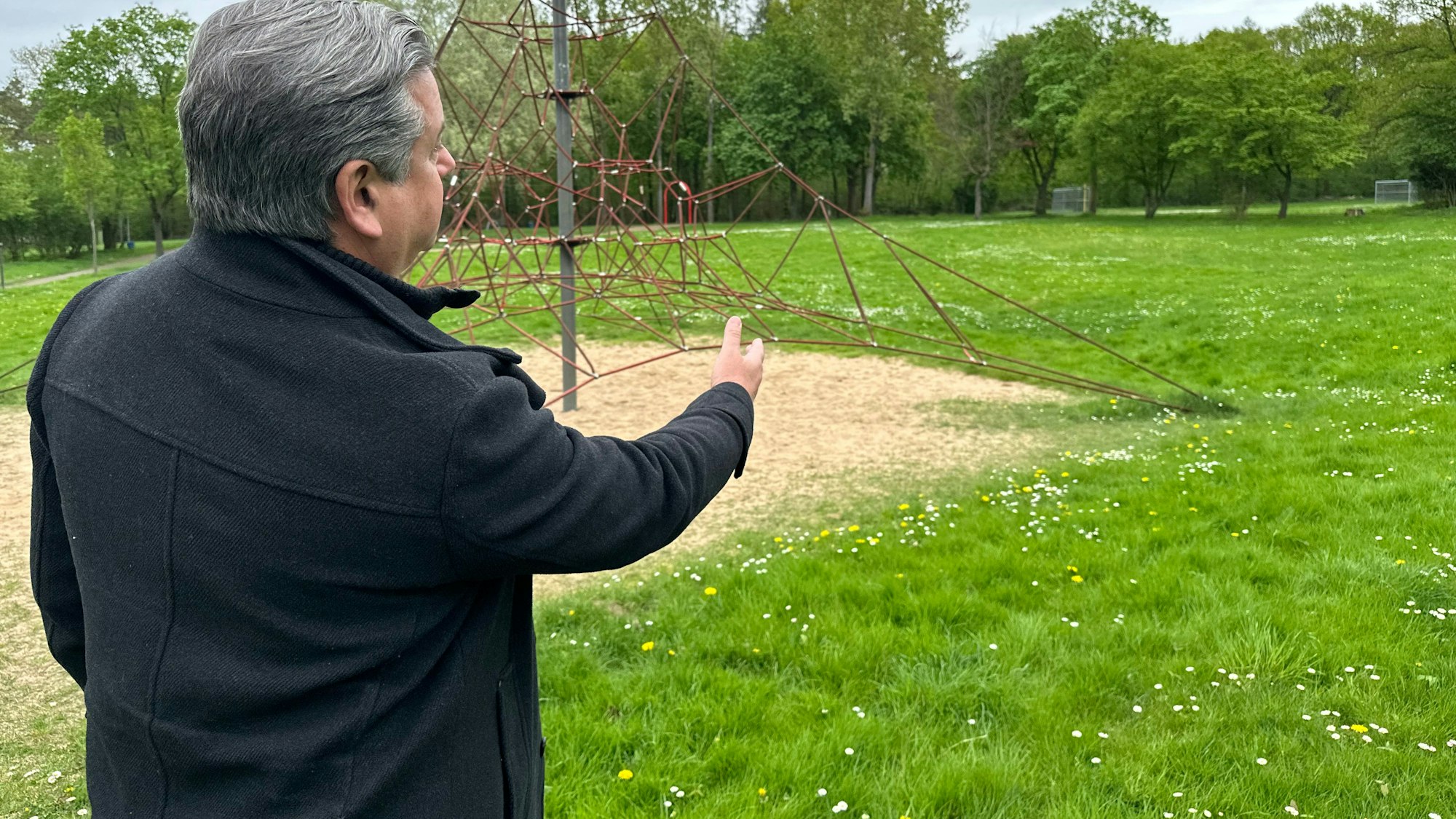Mark Knülle zeigt auf den Spielplatz. Das Hastag-Park wurde auf einer alten Hausmüllkippe angelegt. Jetzt gibt es Senken im Boden.