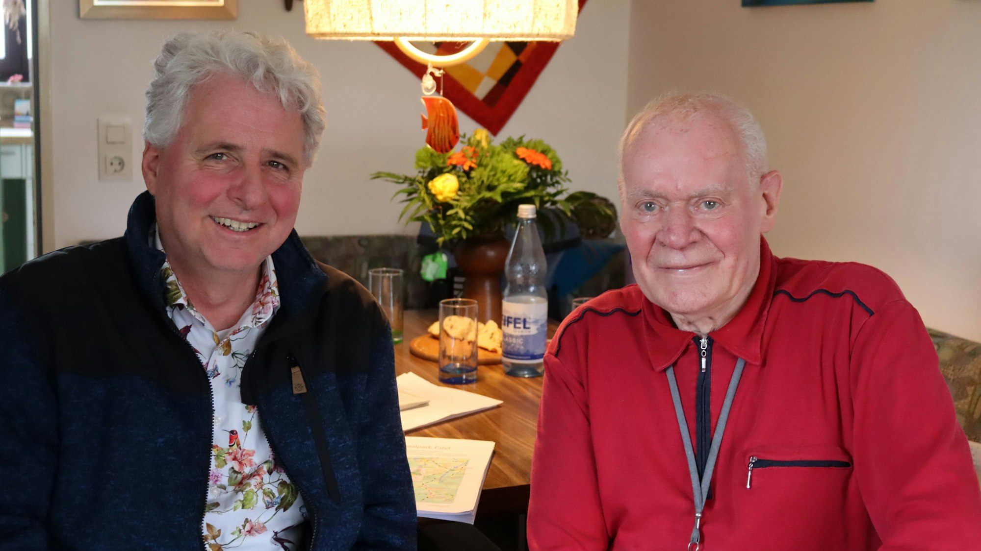 Hansbert Schruff und Wolfgang Müller sitzen an einem Tisch und blicken freundlich in die Kamera.