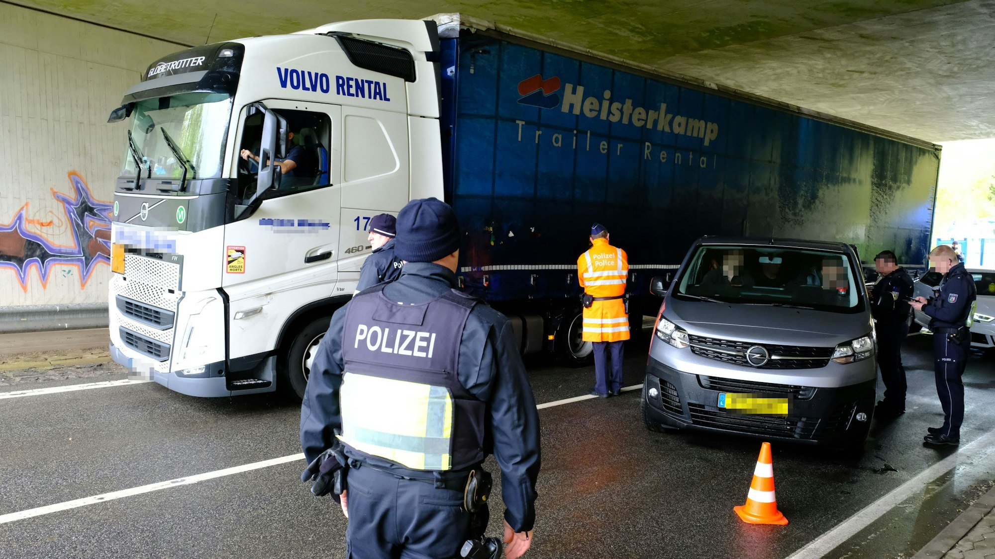 Beamte aus Deutschland und Belgien an einer gemeinsamen Kontrollstelle der Polizei an der B51 bei Dahlem-Baasem. Ein Lastwagen fährt vorbei, Polizisten stehen an einem Kleinbus mit luxemburgischen Kennzeichen.