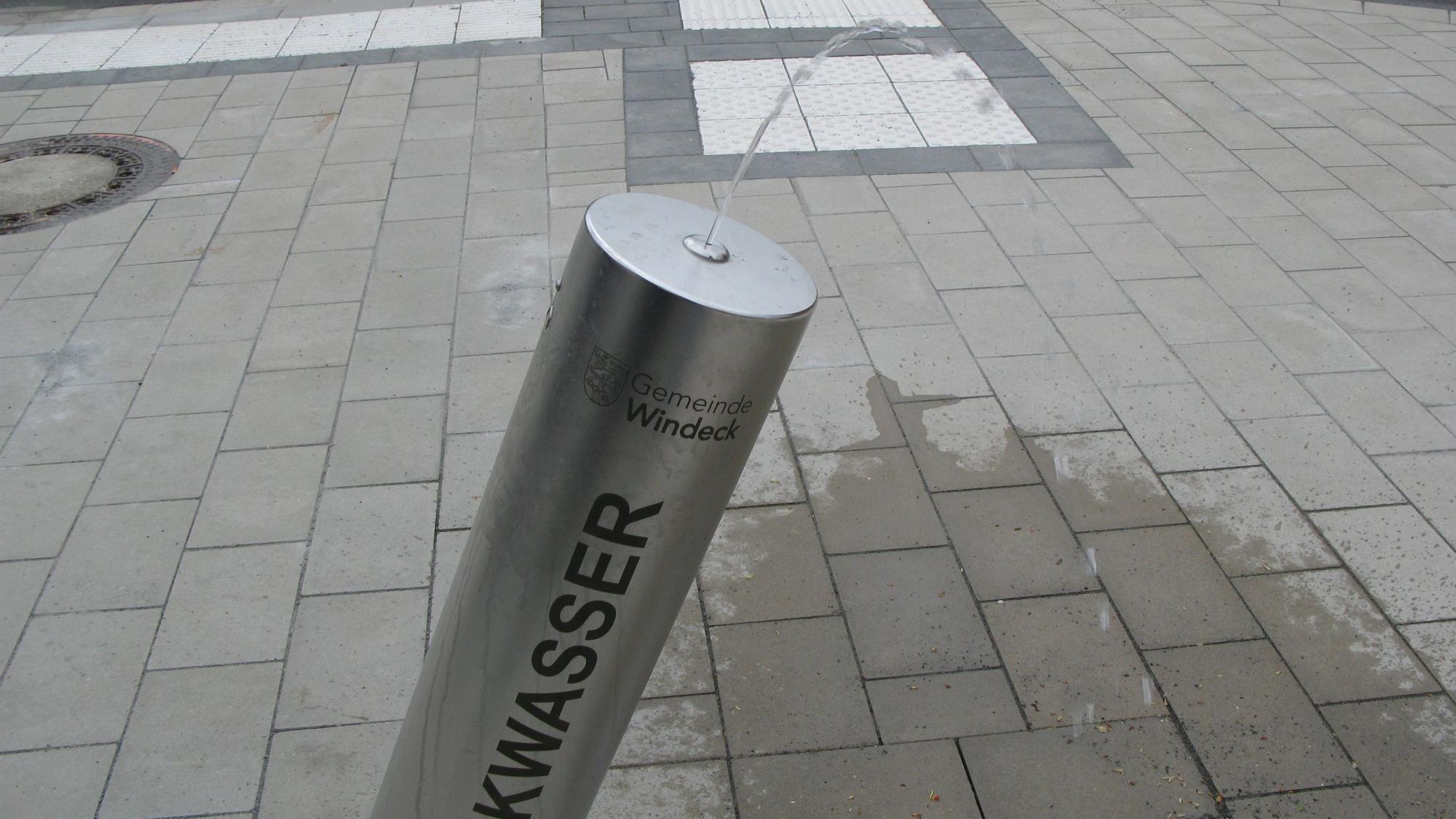 Aus einer schräg stehenden Stahlsäule kommt ein Trinkwasserstrahl.