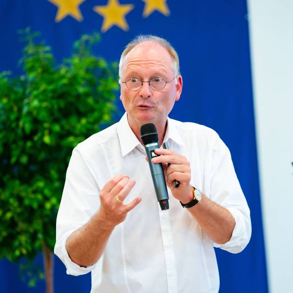 Wetterexperte und Meteorologe Sven Plöger hält bei einem Vortrag ein Mikrofon in der Hand. Er trägt ein weißes Hemd und eine Uhr.