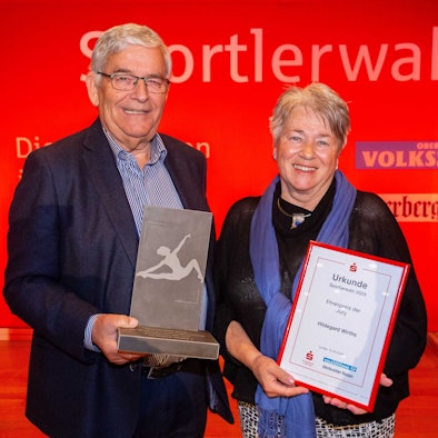 Hagen Jobi überreicht Hildegard Wirths eine Urkunde und eine Skulptur aus Grauwacke.