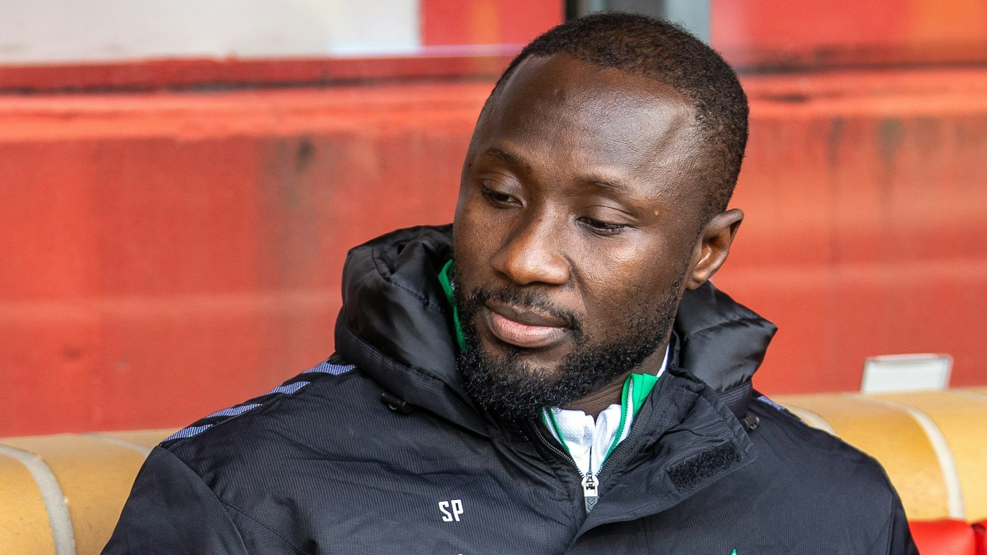 Naby Keita von Werder Bremen sitzt auf der Bank und blickt nach unten.