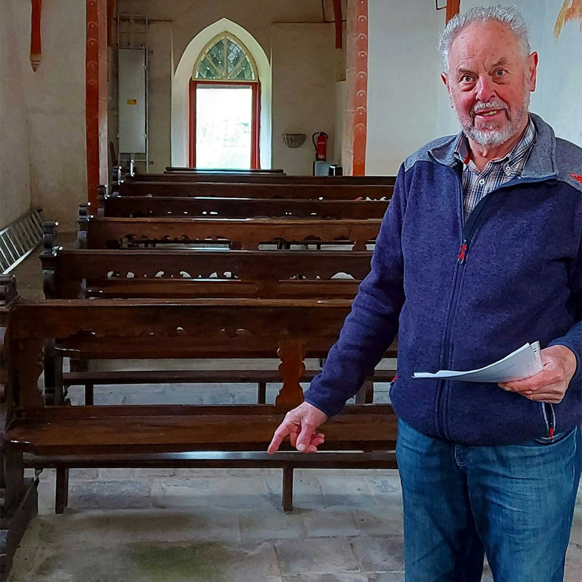 Günter Schneider zeigt auf die Grabplatten in der Kirche.